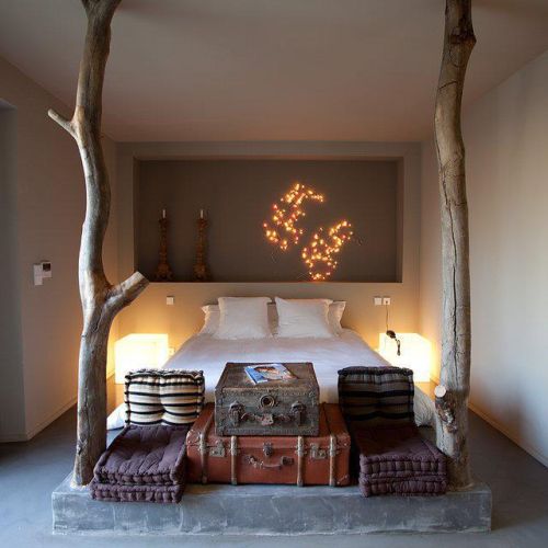 Klimatyczna sypialnia z pniami, walizkami i ciepłym światłem.